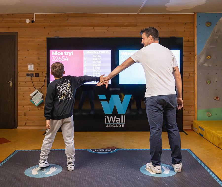 Vater und Sohn geben sich High Five vor der iWall Arcade mit Highscore-Anzeige