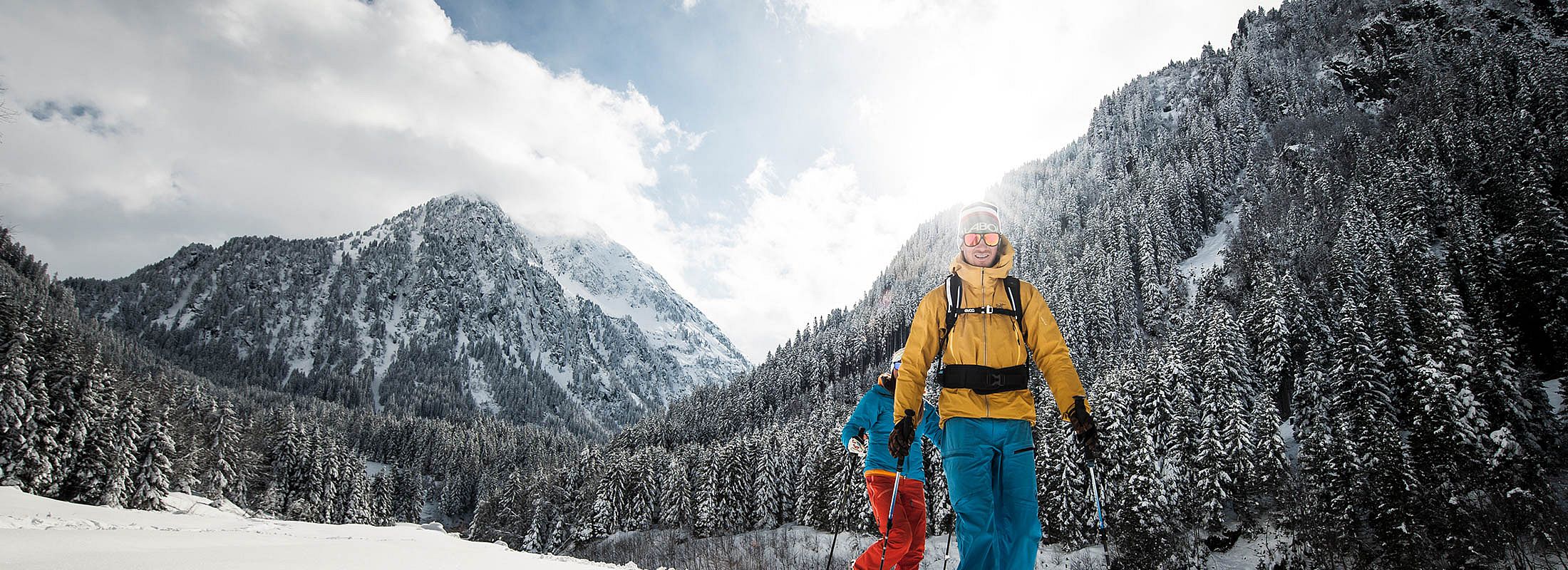 Zwei Winterwanderer in bunter Ausrüstung gehen durch tief verschneite 