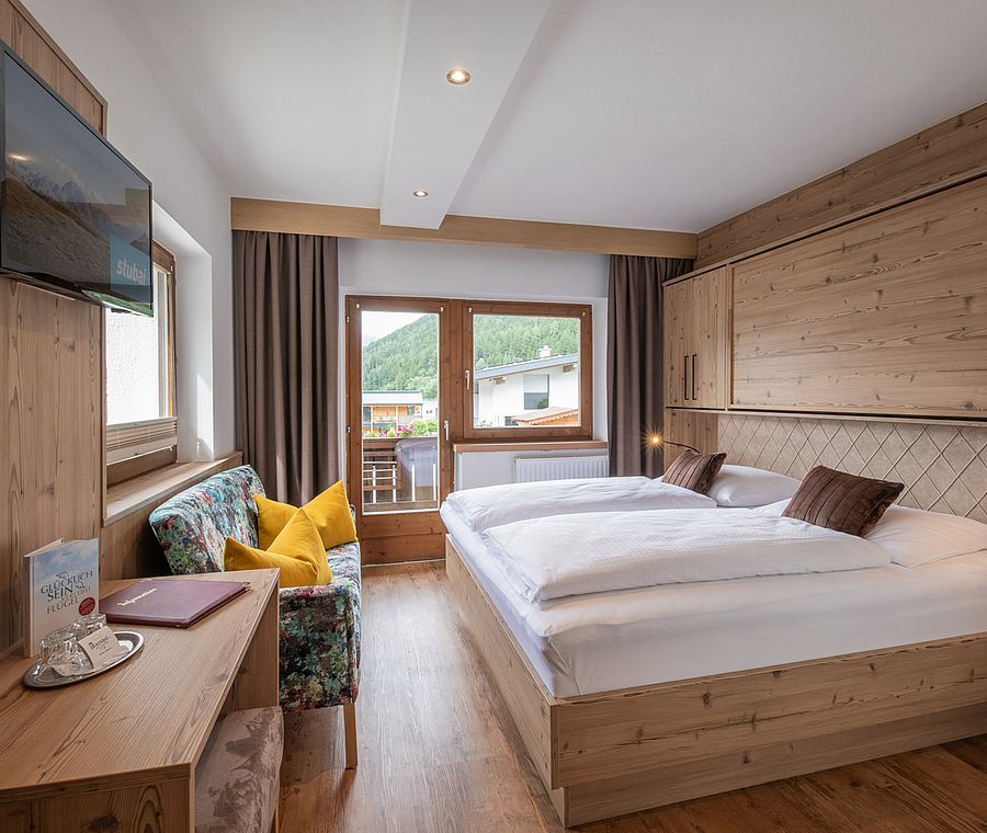 Komfortables Doppelzimmer mit Balkon, Sitzgelegenheit und Holzverkleidung im Hotel Auenhof.